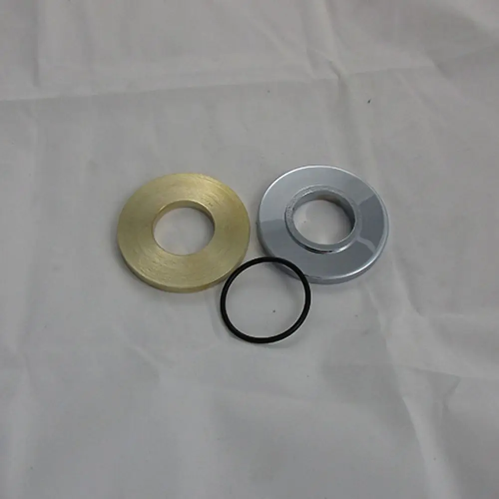 Drei runde Metallteile in verschiedenen Farben (gold, chrom und schwarz) auf hellem Hintergrund, möglicherweise Ersatzteile von Kludi.